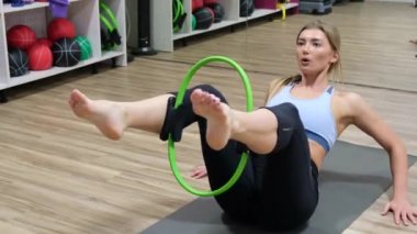 Spor salonunda çömelmiş atletik kadınları kapatın. Formda iki kız, vücut geliştirmek için direnç bandıyla egzersiz yapıyor..