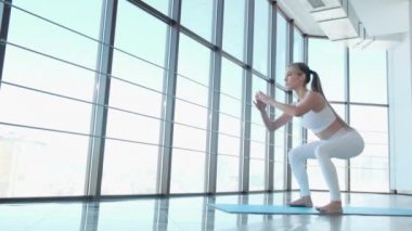 Kız spor salonunda bacaklarını çalıştırmak için egzersiz yapıyor.