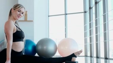 Atletik kız sicimin üzerinde oturuyor. Sarışın yoga yapıyor.