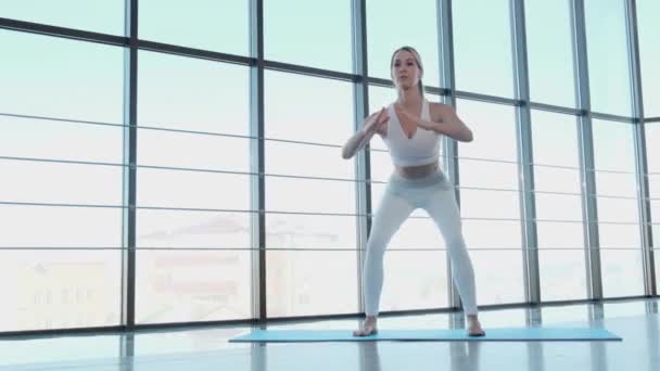 Treinador de fitness feminino fazendo exercícios em l estúdio com grandes janelas. — Vídeo de Stock