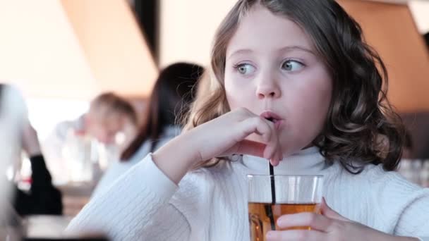 女の子子供はストローを通してジュースを飲む. — ストック動画