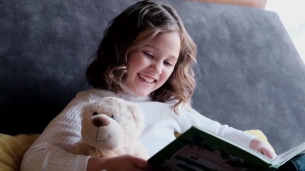 Retrato de uma menina alegre sentada com um ursinho de pelúcia. — Vídeo de Stock