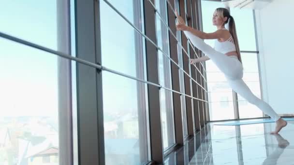 Sportliche Frau am Fenster demonstriert Flexibilität im Fitnessstudio. — Stockvideo