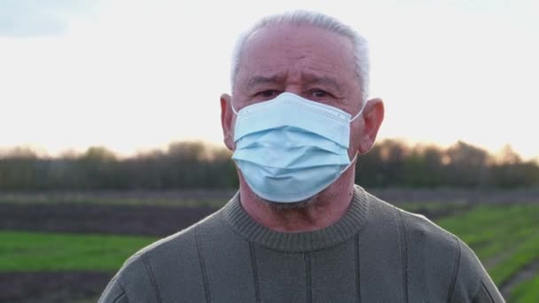 Um homem idoso com uma máscara médica olha para a câmera. — Vídeo de Stock