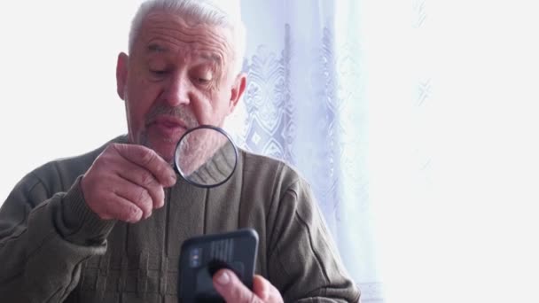 Un pensionato legge un messaggio su uno smartphone — Video Stock