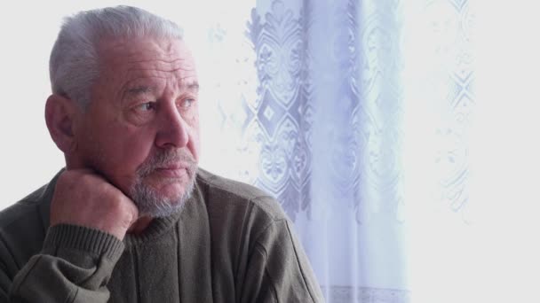 Un vieil homme solitaire regardant par la fenêtre. Homme retraité. — Video
