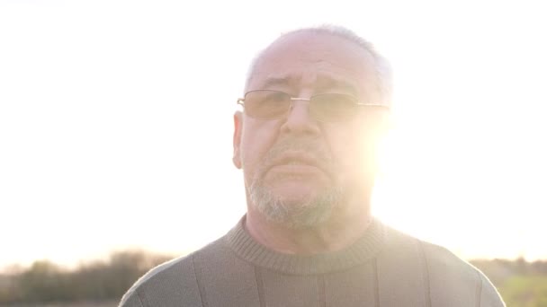 El rostro de un hombre mayor sobre un fondo de luz solar. — Vídeos de Stock