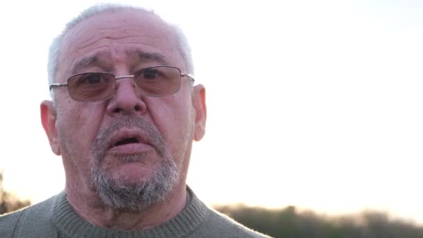Retrato de un hombre mayor de pelo gris sobre un fondo de luz solar — Vídeos de Stock