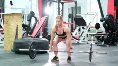 Atletik kadın halterle egzersiz yapıyor, spor salonunda halter kaldırıyor..