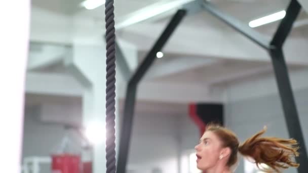 Mujer deportiva fuerte entrena en una cuerda en el gimnasio. — Vídeos de Stock