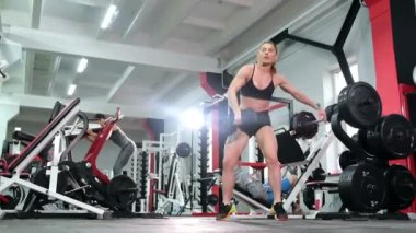 Sporcu büyük profesyonel bir spor salonunda ağır bir dambılı kaldırır..