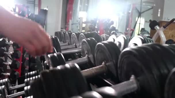 Athletic woman takes two dumbbells to train arm muscles. — Stock Video