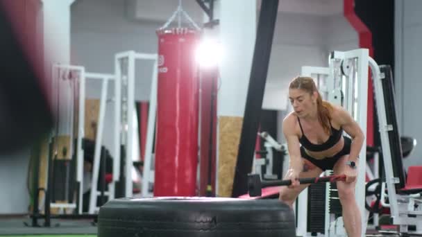 A sporty woman hits a tire with a hammer. — Stock Video