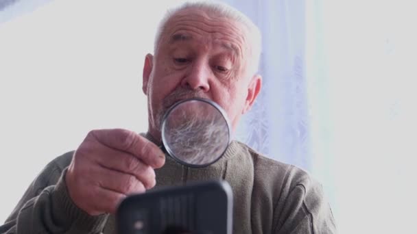 Oude opa gebruikt een smartphone. — Stockvideo