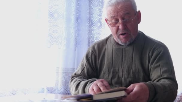 寂しい老人が家で本を読む. — ストック動画
