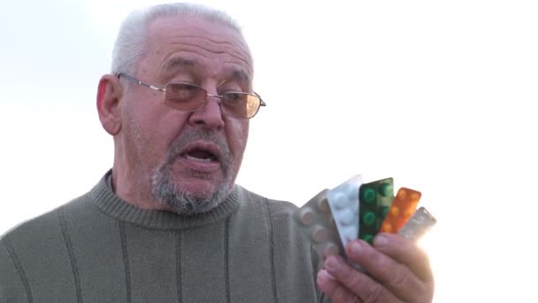 Alter grauhaariger Mann, Großvater mit Tabletten in der Hand. — Stockvideo