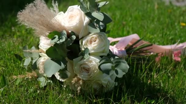 Schöner Hochzeitsstrauß der Braut liegt im grünen Gras — Stockvideo
