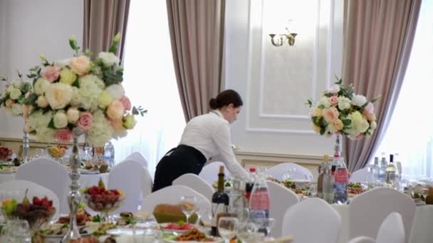 Girl waiter serves food on a festive table. — Stock Video