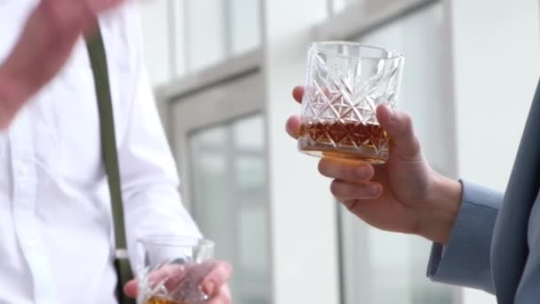 Twee handen in een glas cognac whisky.. — Stockvideo