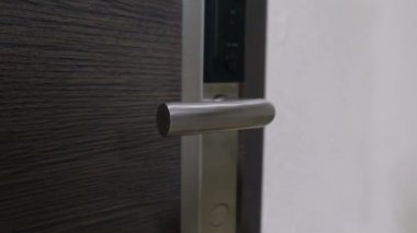 Bir adam parlak bir kapı kolunu alır ve modern, güzel bir kapı açar..