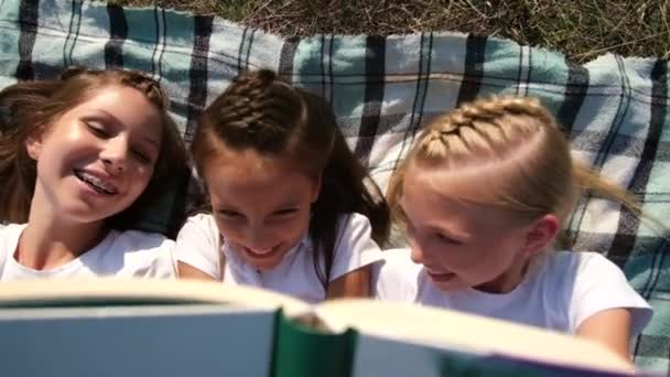 Le ragazze si trovano su una coperta in natura e leggere un libro. Buone vacanze nel campo. — Video Stock