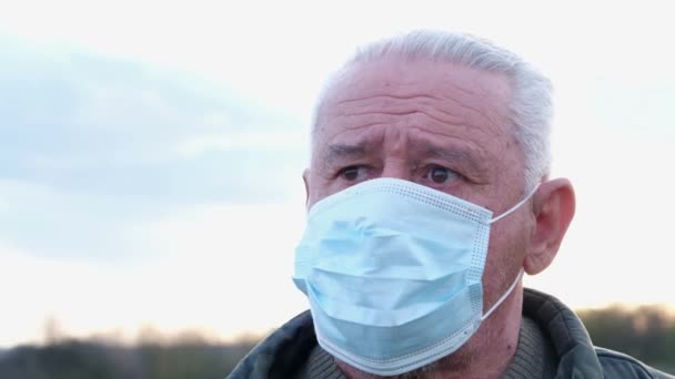 Occhiata preoccupata di nonno in una maschera medica protettiva. — Video Stock