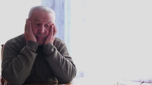 Un viejo abuelo de pelo gris sufre de dolor de cabeza.. — Vídeos de Stock