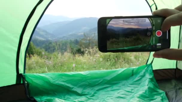 El viajero toma fotos en un teléfono inteligente de un paisaje de montaña después de escalar las montañas alpinas — Vídeo de stock