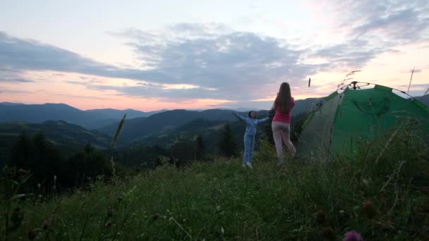 Két lányt fotóznak a hegyekben naplementekor. — Stock videók