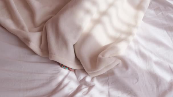 这个女人躺在床上，早上用毯子盖住，女人的腿在上面看 — 图库视频影像