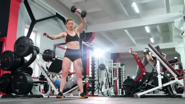 Fitness una atleta musculosa se entrena en el gimnasio con pesadas pesas. — Vídeos de Stock