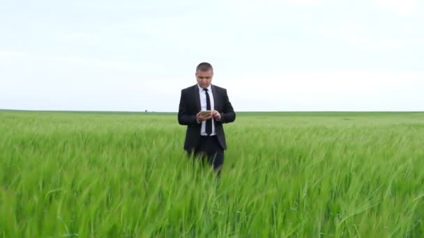 Zakenman agronomist met een tablet evalueert de zaailingen van graangewassen. — Stockvideo