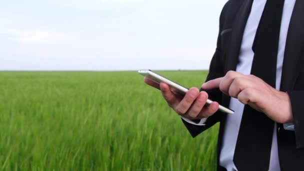 Podnikatel používá bílý tablet na pozadí zeleného pole. — Stock video
