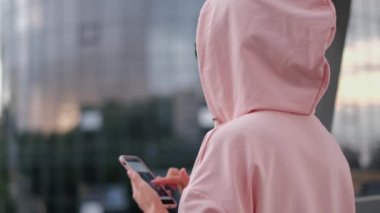 Elinde akıllı bir telefonla pembe takım elbiseli bir kız. Güzel bulanık arkaplan.