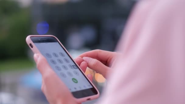 Mädchen im rosafarbenen Anzug mit Smartphone in der Hand. Schöner verschwommener Hintergrund. — Stockvideo