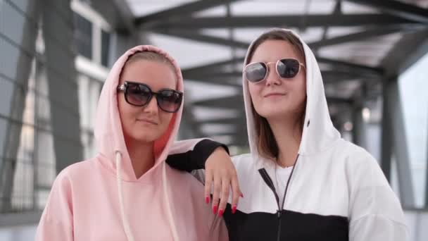 Two girls posing for a photo, they are in hoods and sunglasses. — Stock Video