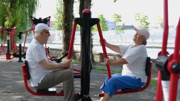 屋外のシミュレーターでスポーツをしている高齢者のカップル. — ストック動画