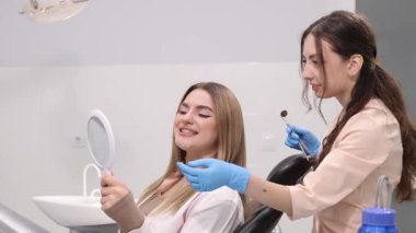 Neşeli ve olumlu bir diş muayenesi, tedaviden sonra güzel gülümsemesine hayran olan mutlu bir hastayı gösteriyor.