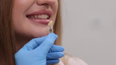 Bir dişçi bir müşterinin gülümsemesini ve genel görünümünü arttırmak için bir kaplama işlemini gösterir