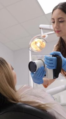 Profesyonel bir diş hekimi modern bir klinikte hasta muayenesi için röntgen cihazı hazırlar..