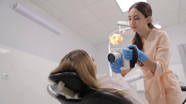 Çok yetenekli bir dişçi modern bir diş muayenehanesindeki hastayı ayrıntılı bir şekilde incelemek için ileri teknoloji kullanıyor.