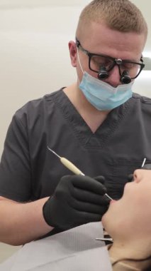 Profesyonel bir dişçi, parlak ve çağdaş bir diş muayenehanesi içindeki hastaya aktif bir diş tedavisi uygular, hassasiyeti, hijyeni ve modern sağlık hizmetlerini vurgular.