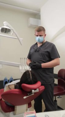 Profesyonel bir diş hekimi, parlak ve modern bir klinikte bulunan hastaya diş bakımının önemli yönlerini, iletişim, güven ve profesyonel oral sağlığa odaklanarak açıklar..