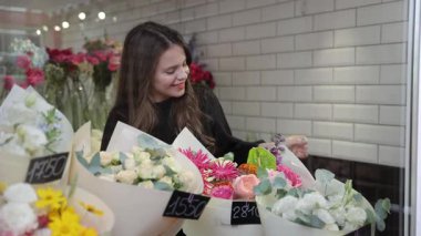 Neşeli bir kadın, büyüleyici bir çiçekçiden güzel ve canlı çiçek buketleri seçerken ışıl ışıl gülümser.