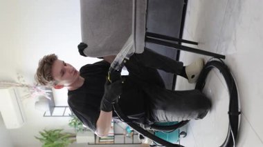 Yetenekli bir profesyonel şık bir ev ortamında modern ekipmanlarla döşemeleri temizler ve yeniler.