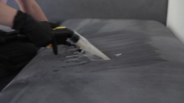 Yetenekli bir teknisyen, en uygun sonuçlar için özel aletler kullanarak kanepenin derin temizliğini yapar.