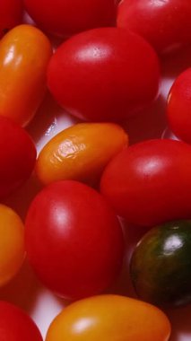 Beyaz bir arkaplanda, doğal tazelik ve canlı renkler sergileyen, çeşitli renklerde taze domateslerin güzel bir çeşidi..