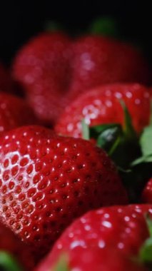 Mükemmel olgun çilekler, koyu bir arka planda güzelce sıralanmış, canlı renklerini, tazeliklerini ve sulu dokularını vurguluyorlar..