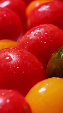Su damlaları serpiştirilmiş taze kiraz domateslerinin yakın plan görüntüsü, doğal tazeliği ve canlı rengi vurguluyor..