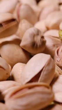 Doğal kabuklarını ve içindeki parlak yeşil çekirdekleri ortaya çıkaran ham fıstıkların detaylı bir yakın çekimi, sağlıklı besin ve beslenme temaları için mükemmel..